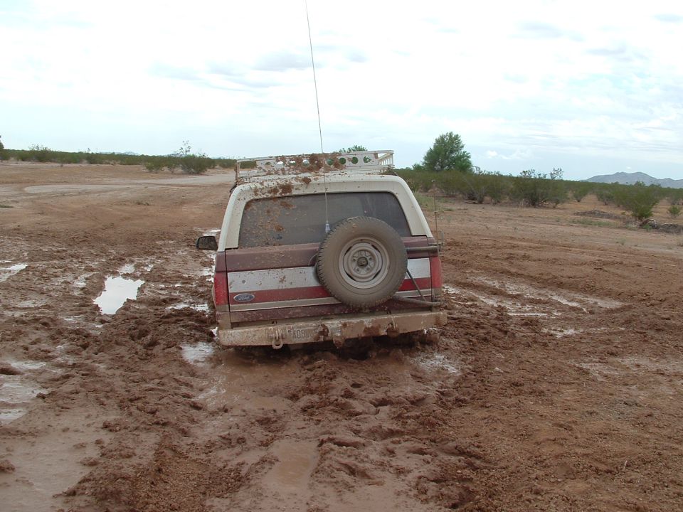1990 Ford Bronco stuck in mud, rear view with spare tire mounted on back