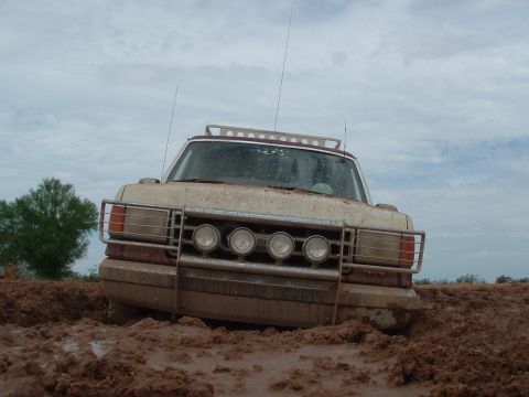 1990 Ford Bronco - This vehicle is deeply embedded in thick mud under a cloudy sky.
