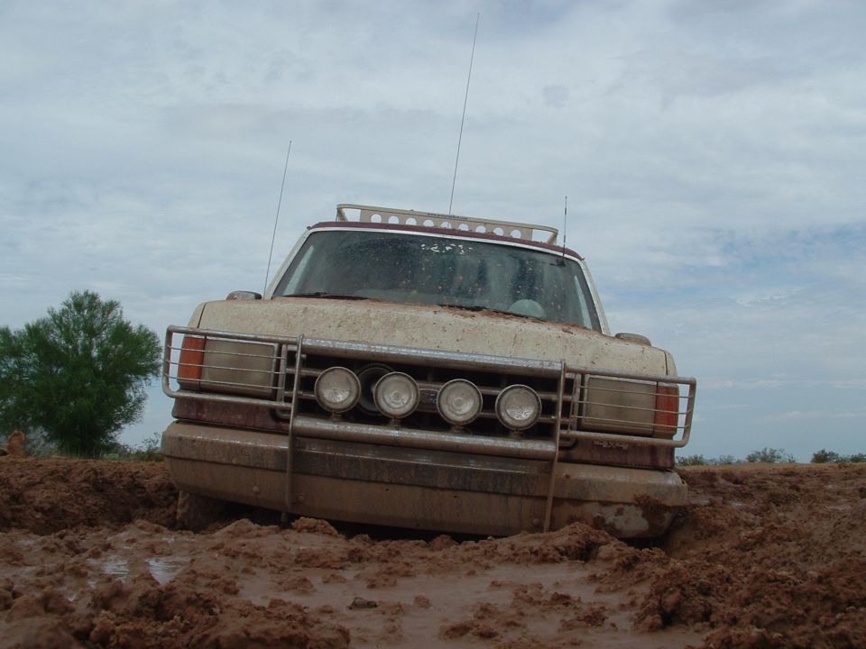 Off-road vehicle stuck deep in mud, front grille and lights visible