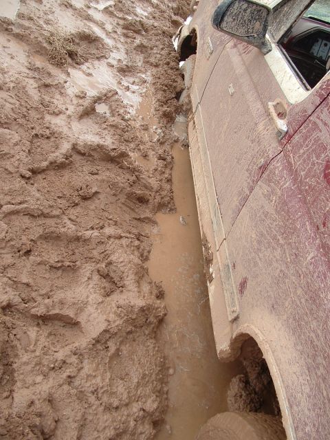 1990 Ford Bronco - Vehicle bogged down in mud, showing the side panel and wheel well submerged.