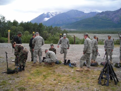 2003 Jeep TJ - A group of soldiers prepare their equipment and weapons in an outdoor area with a mountainous landscape.
