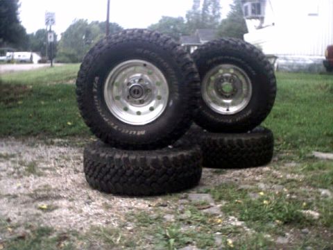1996 Ford Bronco - Set of four off-road tires with chrome rims are displayed outdoors on a grassy area.