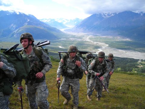 2003 Jeep TJ - Soldiers are hiking through a mountainous terrain with rifles and backpacks.