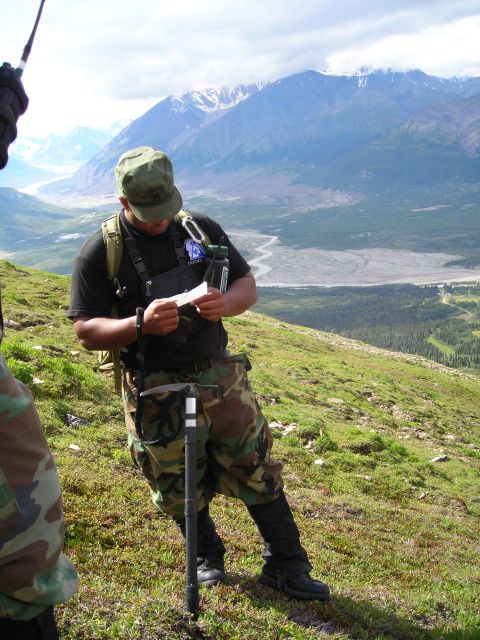 2003 Jeep TJ - A person consults a document while standing on a grassy hillside with a vast valley and mountains in the distance.