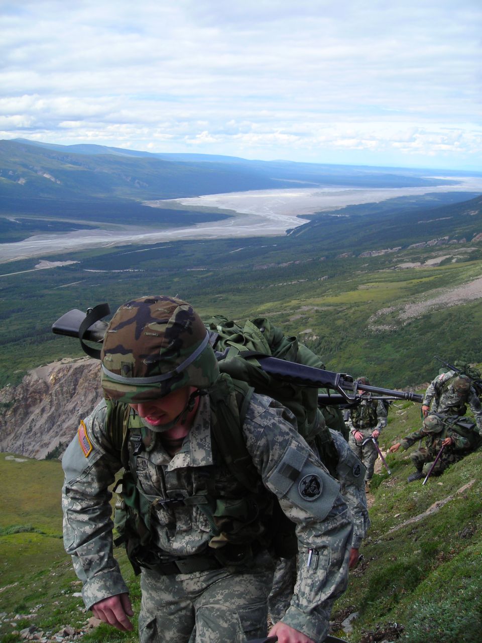Soldiers hiking up a mountain with rifles and backpacks