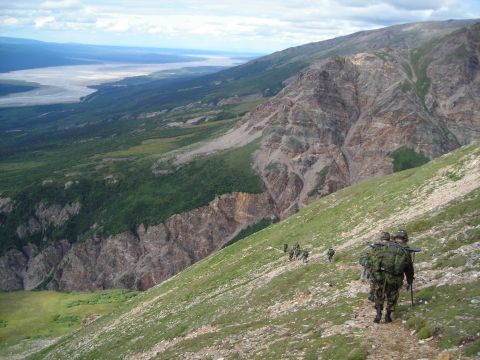 2003 Jeep TJ - A group of soldiers trek along a mountain path, with a vast valley and river visible below.