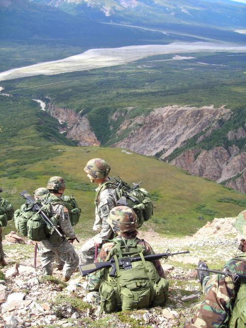 2003 Jeep TJ - A group of soldiers takes a break on a mountain ridge, overlooking a wide, scenic valley with a river.