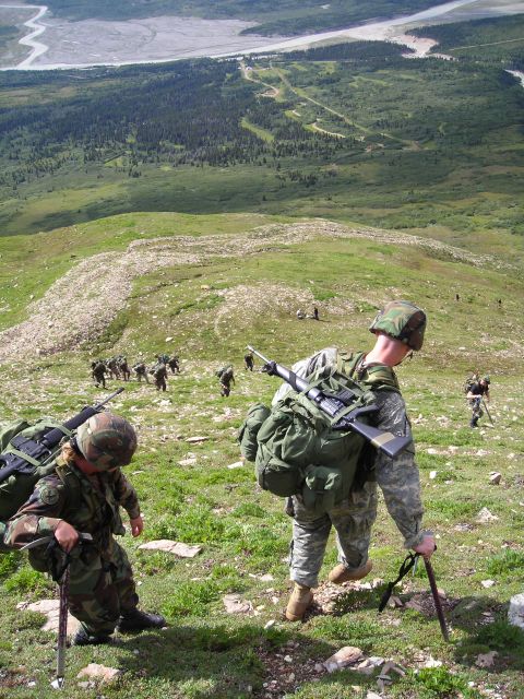 2003 Jeep TJ - A group of soldiers navigates a challenging mountain terrain, carrying their gear and rifles.