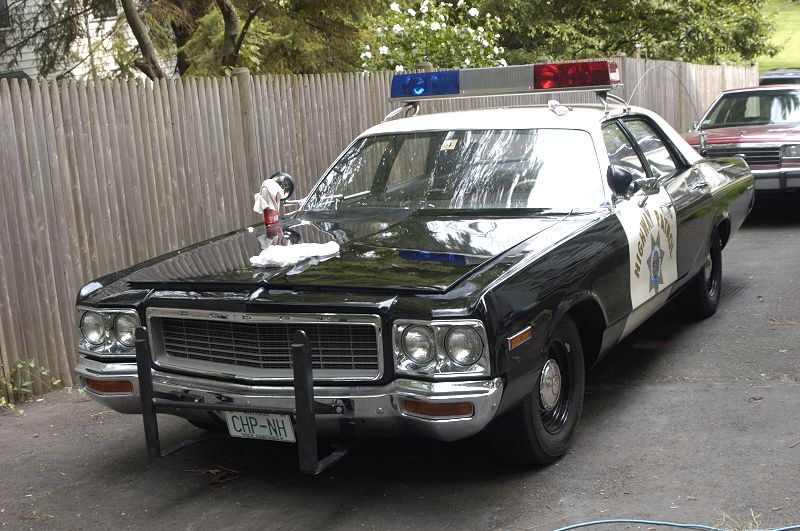 Black and white police car with light bar, CHP-NH license plate
