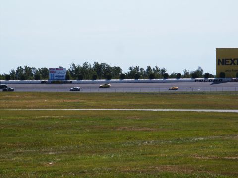 2001 Mercury Grand Marquis - Multiple cars race on a sunny day at Pocono Raceway, with a large yellow sign visible.