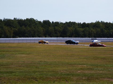 2001 Mercury Grand Marquis - Cars driving on a race track with a treeline in the background.