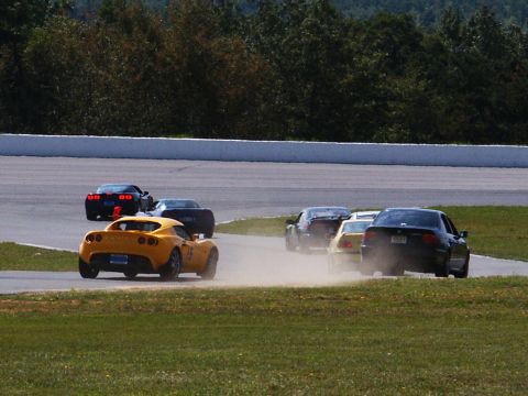 2001 Mercury Grand Marquis - Multiple cars compete on a race track, with a yellow sports car in the foreground.