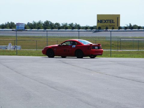 2001 Mercury Grand Marquis - Red coupe with black wheels and a spoiler sits on a race track, showing the number 81 on its door.