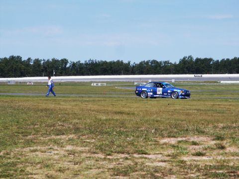 2001 Mercury Grand Marquis - A blue coupe with racing decals drives on a track next to a grassy field.
