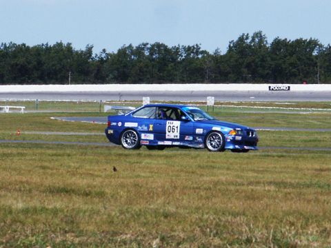 2001 Mercury Grand Marquis - A blue BMW E36 race car with racing decals and number 061 is on the track.