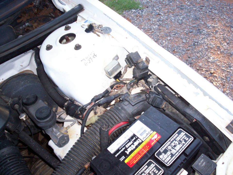 Engine bay with battery, wiring, and keys on white strut tower