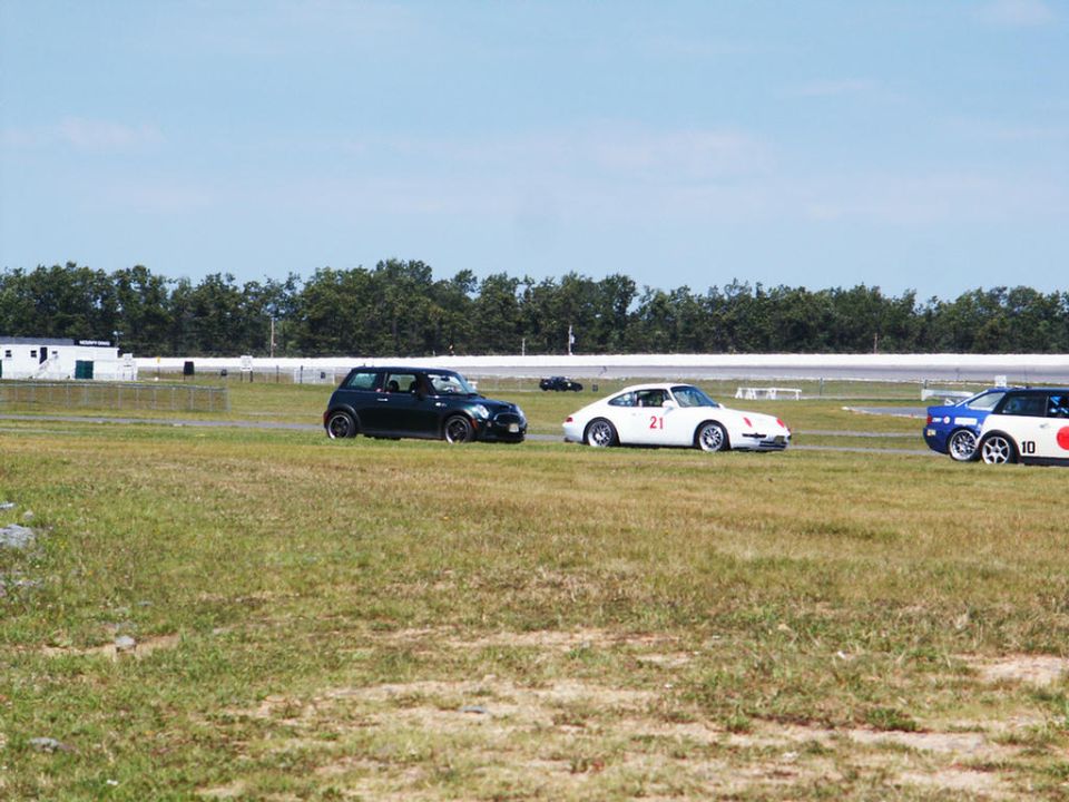 Black Mini Cooper, white Porsche 911, and blue/white race car on track