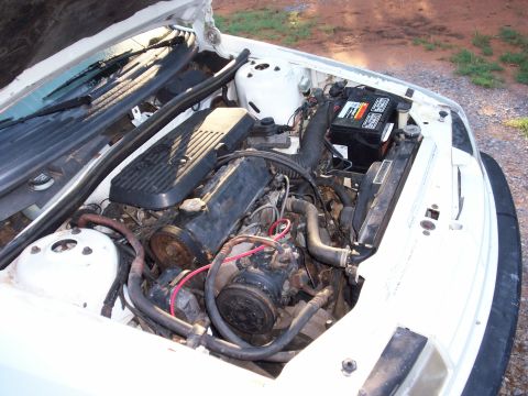 1990 Dodge Shadow - Engine bay of a 1990 Dodge Shadow, showing the engine, battery, and radiator.
