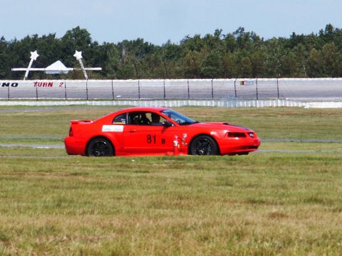 2001 Mercury Grand Marquis - A red Ford Mustang with racing decals and the number 81 is seen on the side during a track event.
