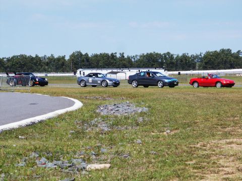 2001 Mercury Grand Marquis - Multiple vehicles participate in an event on a race track under a clear sky.