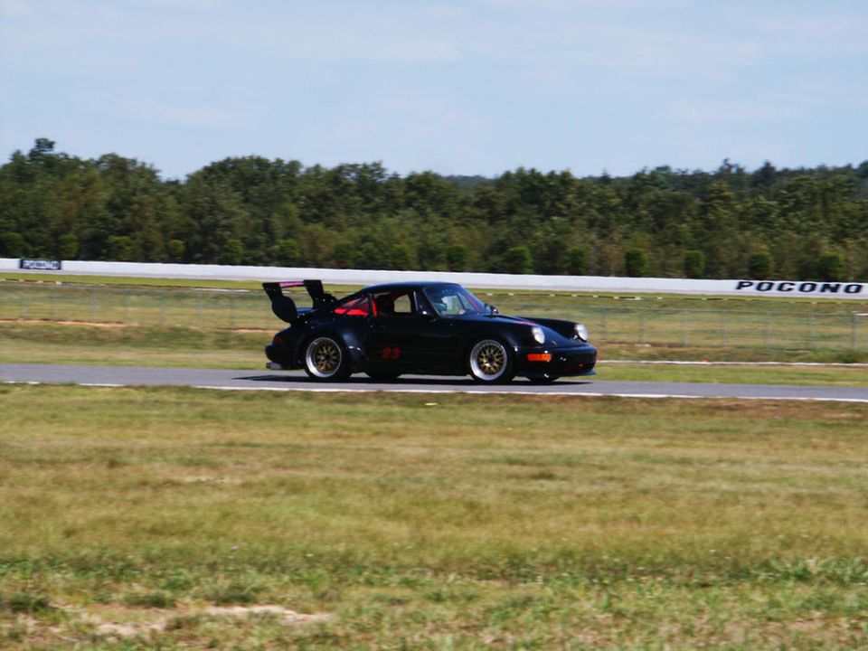 Black racing car with large rear spoiler and number 23 on side, on a track
