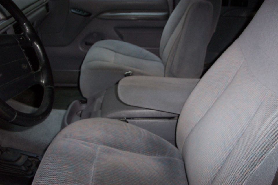 1995 Ford Bronco interior with gray cloth seats, center console armrest, and steering wheel