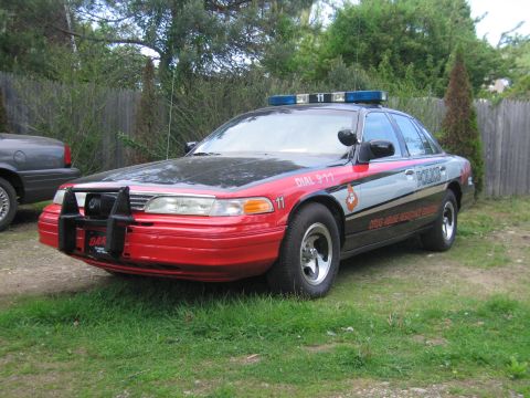 1991 Ford LTD Crown Victoria - Front three-quarter view of a Ford Crown Victoria in black-and-red D.A.R.E. police livery, lettered POLICE, DIAL 9-1-1, and DRUG ABUSE RESI…