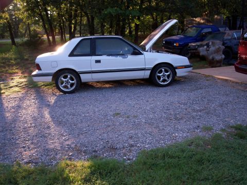1990 Dodge Shadow - White 1990 Dodge Shadow coupe with hood open, parked outdoors with other vehicles visible.