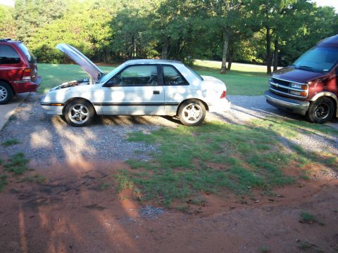 1990 Dodge Shadow - Three vehicles are parked outside on a sunny day, with one car's hood open.