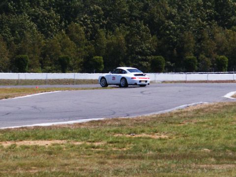 2001 Mercury Grand Marquis - A white sports car with the number 21 on its door navigates a turn on a race track.