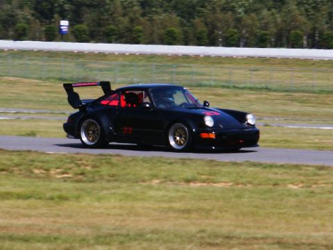 2001 Mercury Grand Marquis - A black Porsche 911 with racing decals is seen on a track, a prominent rear wing and red racing seats.