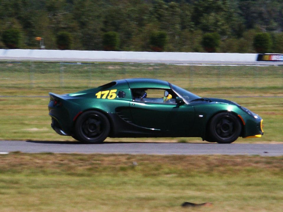 Green sports car with number 175 on the side, on a race track