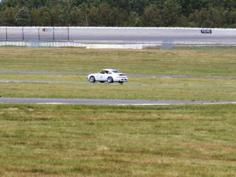 2001 Mercury Grand Marquis - A white sports car with racing number 21 drives on a track with grassy infield.