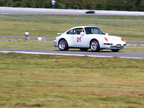 2001 Mercury Grand Marquis - A white Porsche 911 with racing number 21 is captured in a three-quarter front view on a paved track with grassy surroundings.