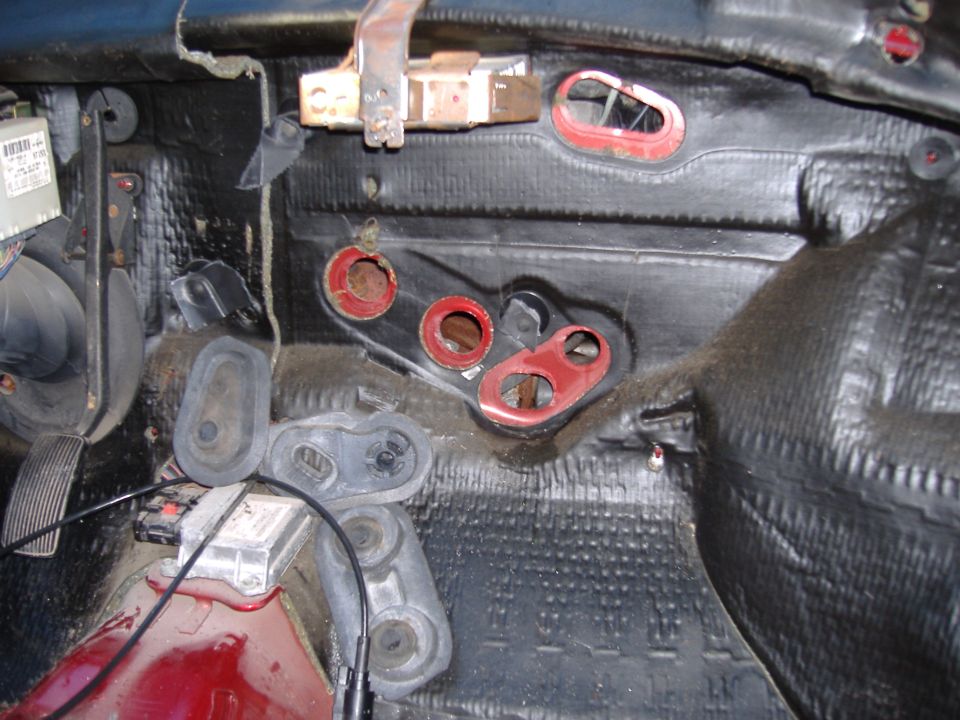 Car interior disassembled, showing insulation and HVAC components. Pedals visible on left