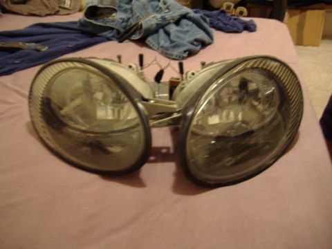 1998 Ford Taurus - Two detached headlights are shown, with wiring visible, against a backdrop of clothing.