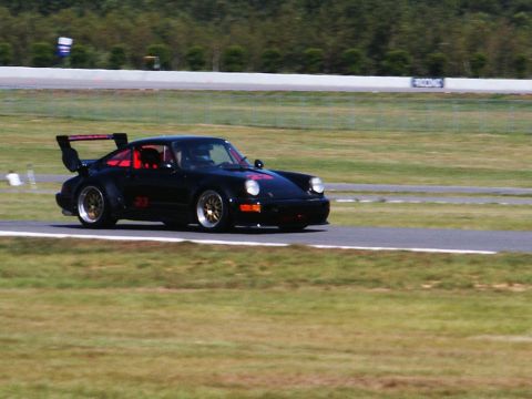 2001 Mercury Grand Marquis - A black Porsche 911 with a prominent rear spoiler and racing numbers is captured on a race track.
