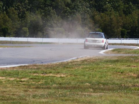 2001 Mercury Grand Marquis - A white car navigates a turn on a race track, generating a cloud of dust.