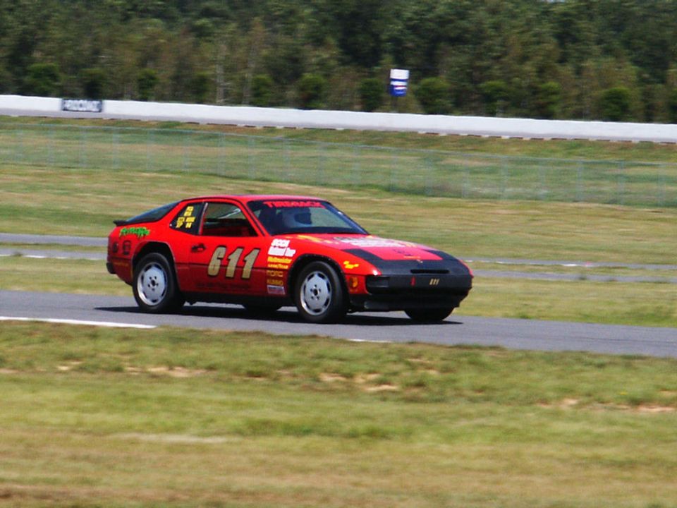 Red race car with number 611 on the door, black hood, on a race track
