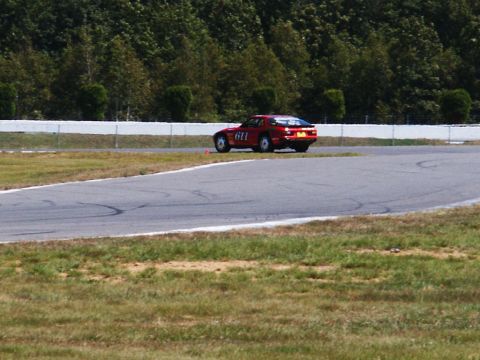 2001 Mercury Grand Marquis - A red sports car is driving on a race track during a sunny day.