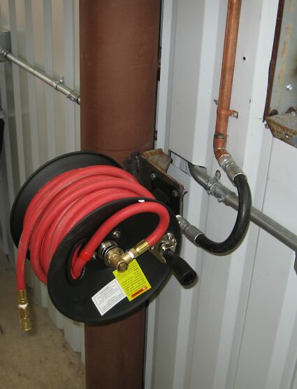 1986 Ford Ranger - An air hose reel is mounted to a large pipe in a workshop setting.
