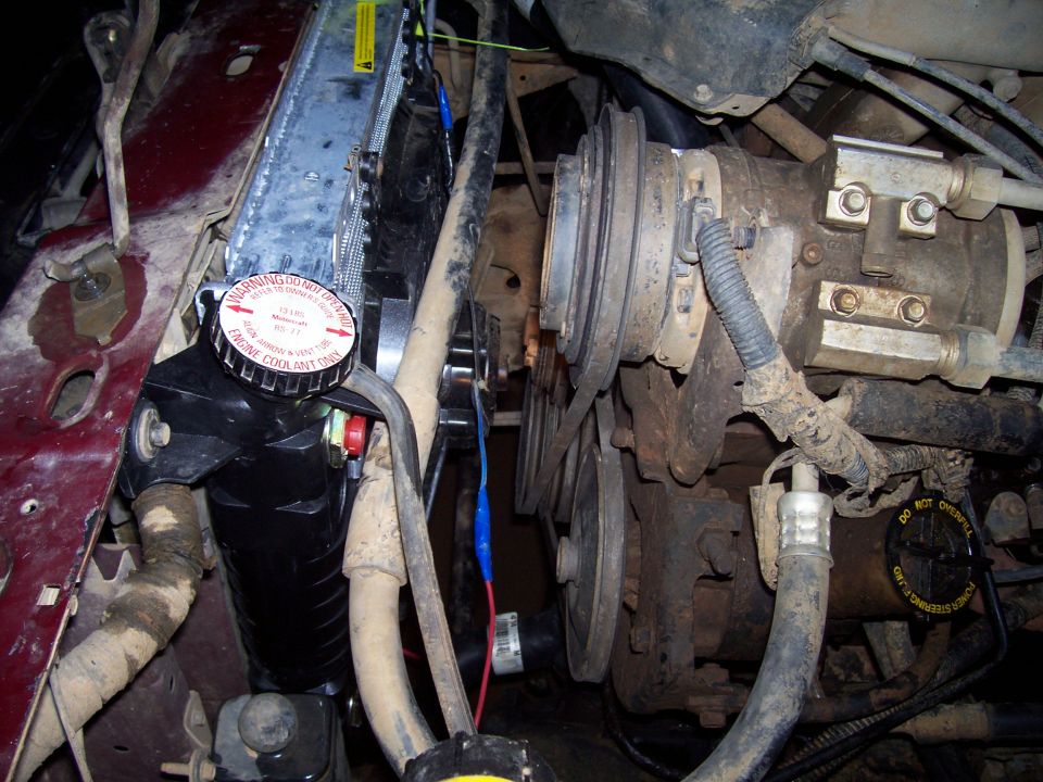 Engine bay showing radiator cap, belt pulleys, and power steering reservoir