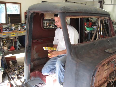 1977 Ford F-150 - A man uses a level inside the interior of a disassembled vintage Ford truck cab.