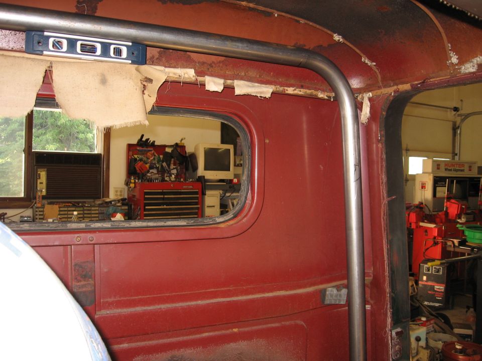Red truck cab interior with roll cage, toolbox, and computer visible through window