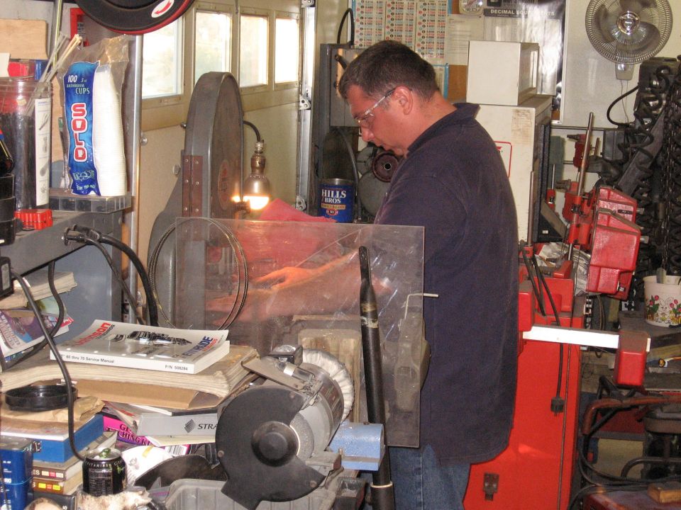 Man working in a cluttered garage with tools and machinery