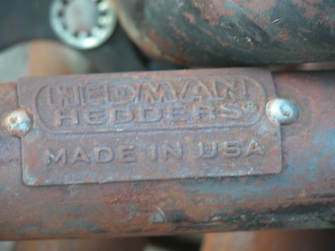 1990 Ford Bronco - Close-up of a rusty exhaust manifold part with visible text indicating its origin.