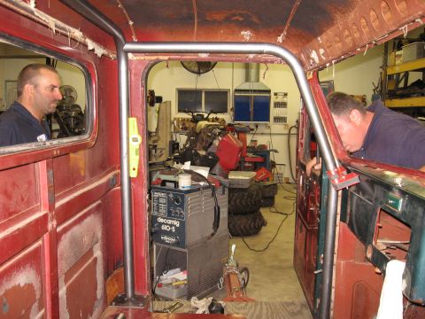1977 Ford F-150 - Installing a roll cage inside a truck's interior with a welding machine nearby.