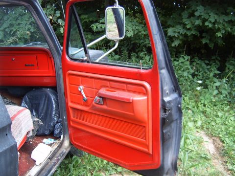 1993 Ford Bronco - Interior view of a truck's red door panel and dashboard, with a black trash bag visible on the floor.