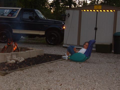 1993 Ford Bronco - A dark blue 1993 Ford Bronco is parked near a fire pit, with a child relaxing in a chair nearby.