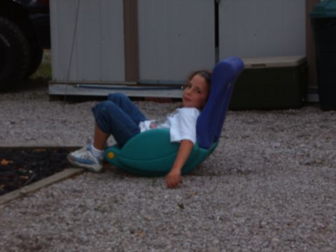 1993 Ford Bronco - Young girl relaxes in a rocking chair outdoors on a gravel lot.